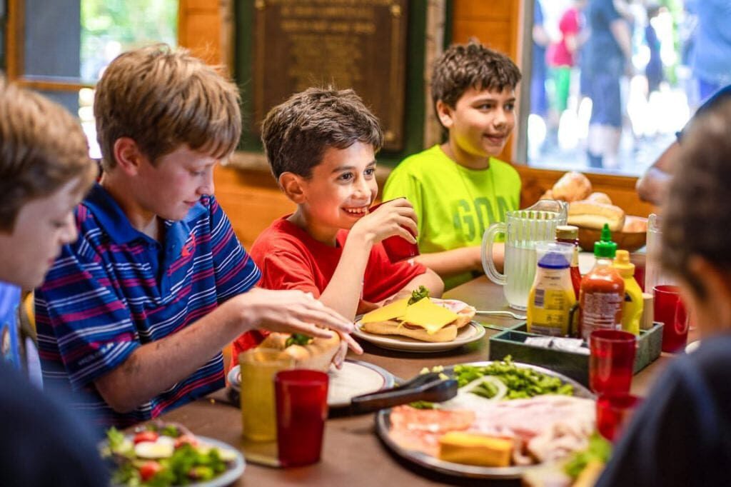 Group of boys eat a meal at summer camp